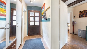 A hallway with a wooden door, a blue mat, and a painting on the wall.