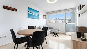 Une pièce moderne comprenant une table à manger, des chaises, un canapé, une lampe et une grande fenêtre.