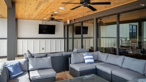 A covered outdoor seating area with a sectional sofa, a glass table, and ceiling fans. - Stay in the spacious 2BR Squad Room in McMinnville, TN! (Mcminnville)