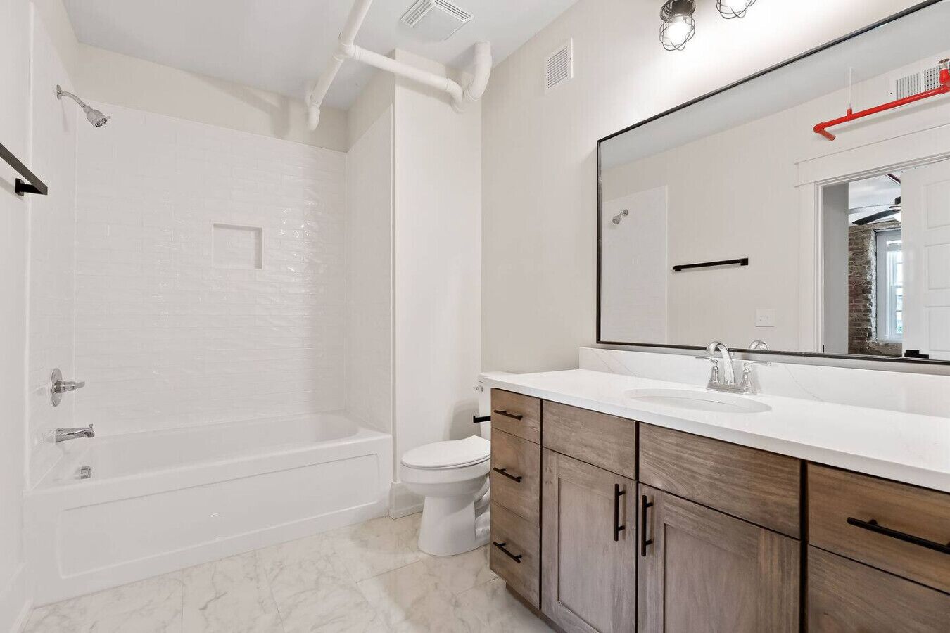 Une salle de bain moderne équipée d’une baignoire, de toilettes et d’un meuble-lavabo avec un miroir.