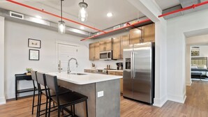 A modern kitchen with a central island, stainless steel appliances, and a dining area with bar stools. - Stay in the spacious 2BR Squad Room in McMinnville, TN! (Mcminnville)