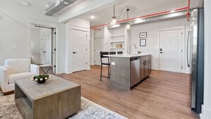 A modern kitchen with a central island, stainless steel appliances, and a dining area with a white sofa and coffee table. - Stay in the spacious 2BR Squad Room in McMinnville, TN! (Mcminnville)