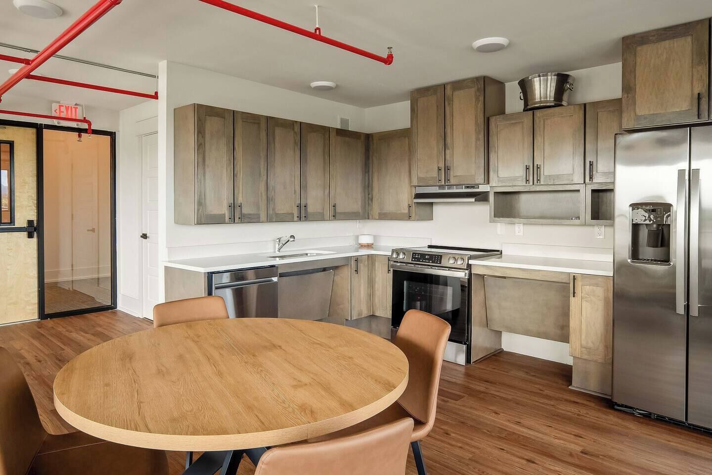 Eine moderne Küche mit Holzausstattung, Edelstahlgeräten und einem runden Holztisch mit Stühlen.