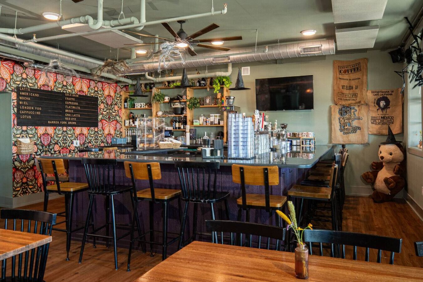 A bar area with a menu board, stools, and a decorative bear statue.