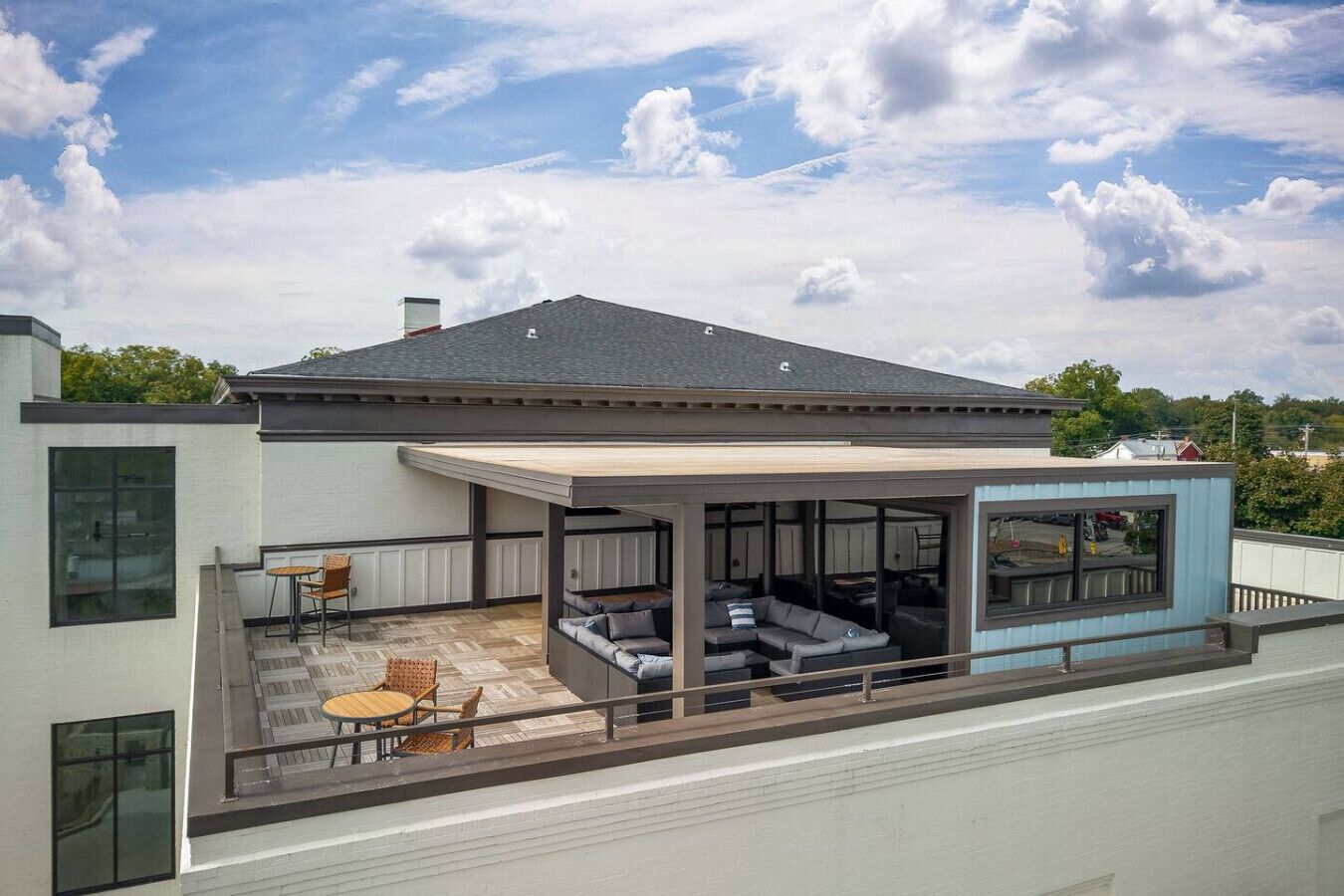 Ein modernes Haus mit überdachter Terrasse, einem großen Fenster und Blick zum Himmel.