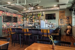 A bar area with a menu board, stools, and a decorative bear statue.