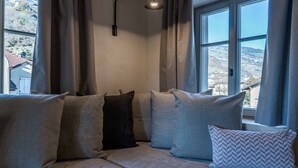 Una habitación acogedora con sofá, ventana con cortinas y lámpara.