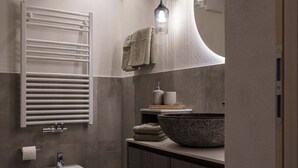 Un baño moderno con un bidé, un espejo grande y un lavabo sobre encimera.