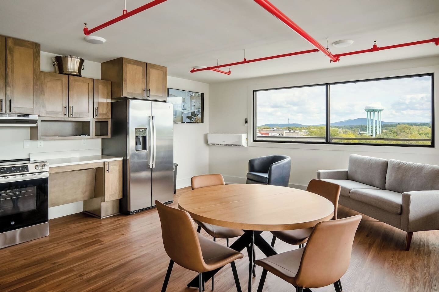 A modern kitchen with stainless steel appliances, wooden cabinets, and a dining area with a round table and chairs.