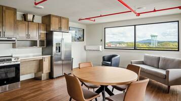 A modern kitchen with stainless steel appliances, wooden cabinets, and a dining area with a round table and chairs.