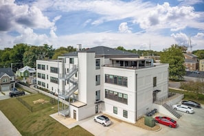 A multi-story building with a fire escape, a covered outdoor area, and a parking lot with cars.
