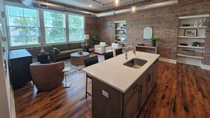 Une cuisine moderne dotée d’un îlot central, un coin repas avec une table ronde et un salon avec un canapé et des fauteuils.