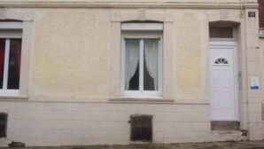 Ein Gebäude mit einer beigefarbenen Fassade, weißen Fenstern und einer weißen Tür mit einem dekorativen Glasfeld.