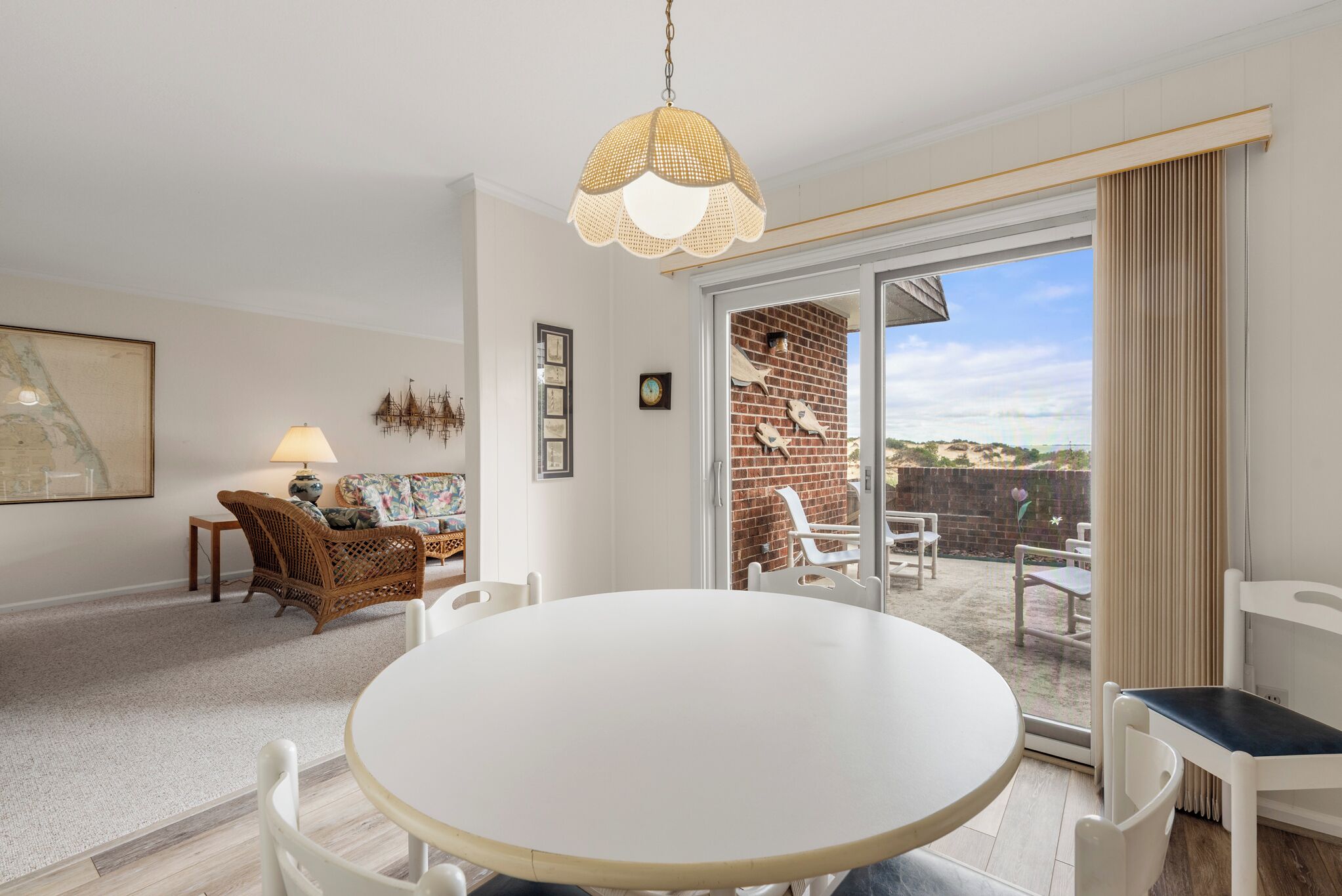 Un coin repas avec une table ronde et des chaises, un canapé en osier et un luminaire suspendu.