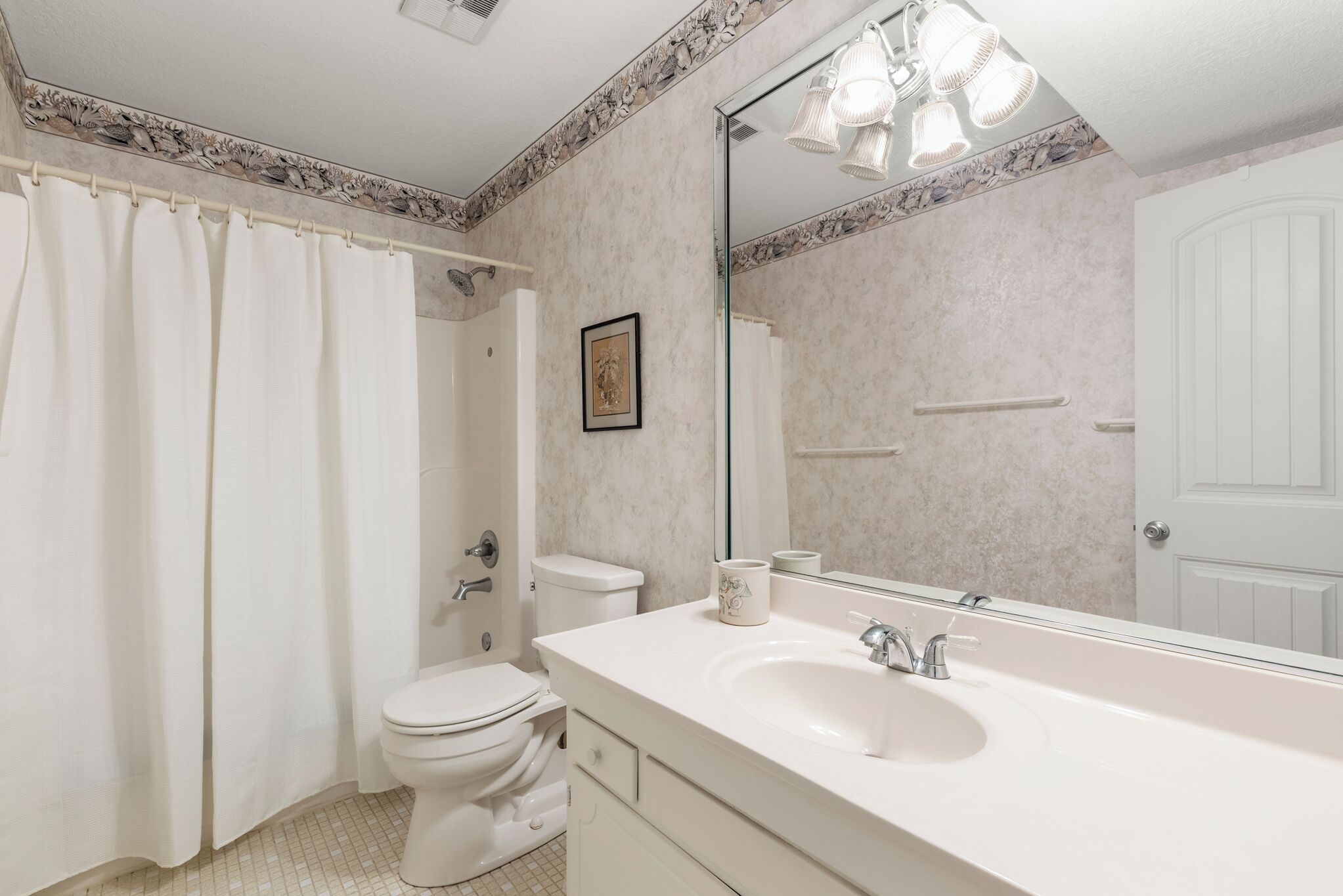 A bathroom with a white sink, toilet, and shower curtain.