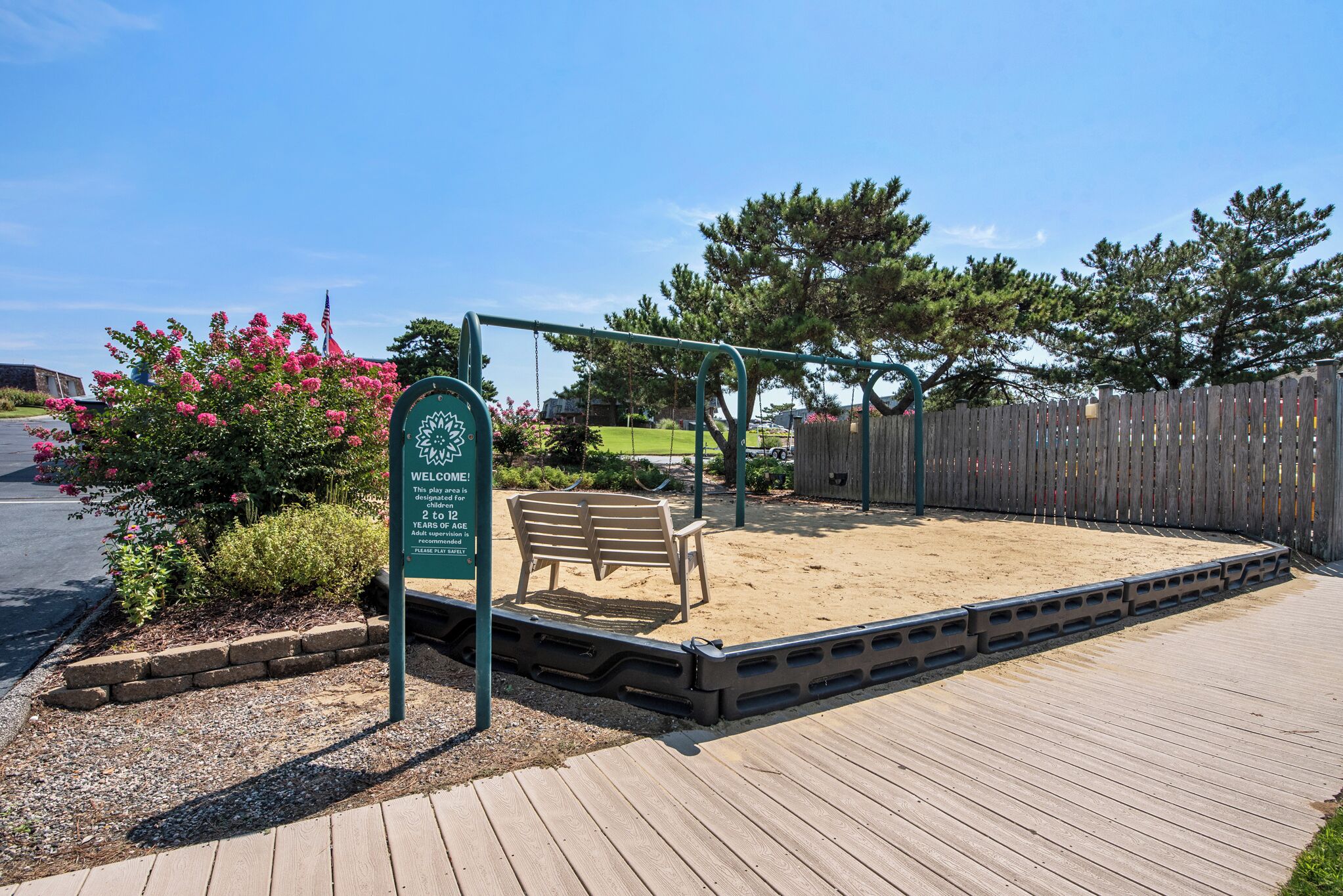 A playground with a swing set, a bench, and a sandpit.
