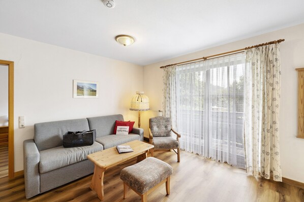 A living room with a sofa, armchair, wooden coffee table, and a lamp.
