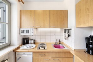 A compact kitchen with wooden cabinets, a microwave, a coffee maker, and a sink. - Apartment 'Fewo Brünnstein - No. 44 Pool, Sauna' with Mountain View, Shared Garden & Wi-Fi (Oberaudorf)