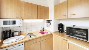 A modern kitchen with wooden cabinets, a microwave, toaster, sink, and a built-in oven.