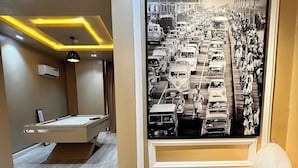 Un intérieur moderne agrémenté d’une grande photographie en noir et blanc représentant une rue animée, d’un banc en bois orné d’objets décoratifs et d’un design minimaliste avec un éclairage encastré.