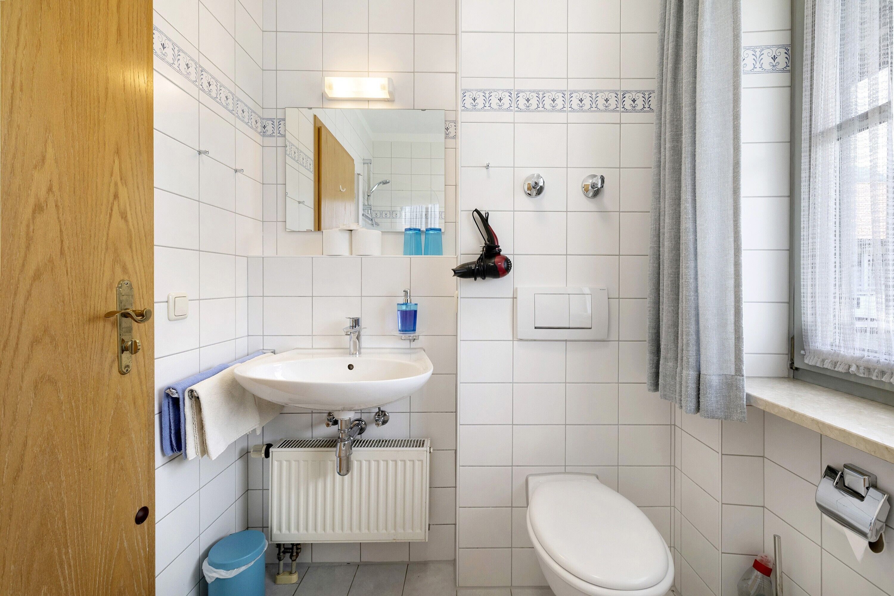 Een badkamer met een wit wastafel, toilet en spiegel.