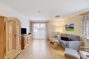 Un salon comprenant un canapé, un meuble en bois, une télévision et une table.