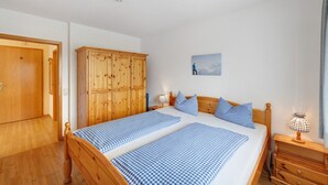 A bedroom with two beds, wooden wardrobe, bedside tables, and a painting on the wall. - Apartment 'Fewo Brünnstein- Nr 28 Pool, Sauna' with Mountain View, Shared Garden & Wi-Fi (Oberaudorf)