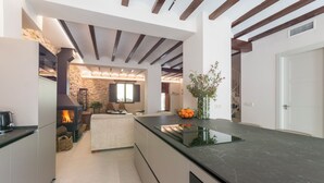 Una cocina moderna con pared de piedra, chimenea y comedor con mesa y sillas.