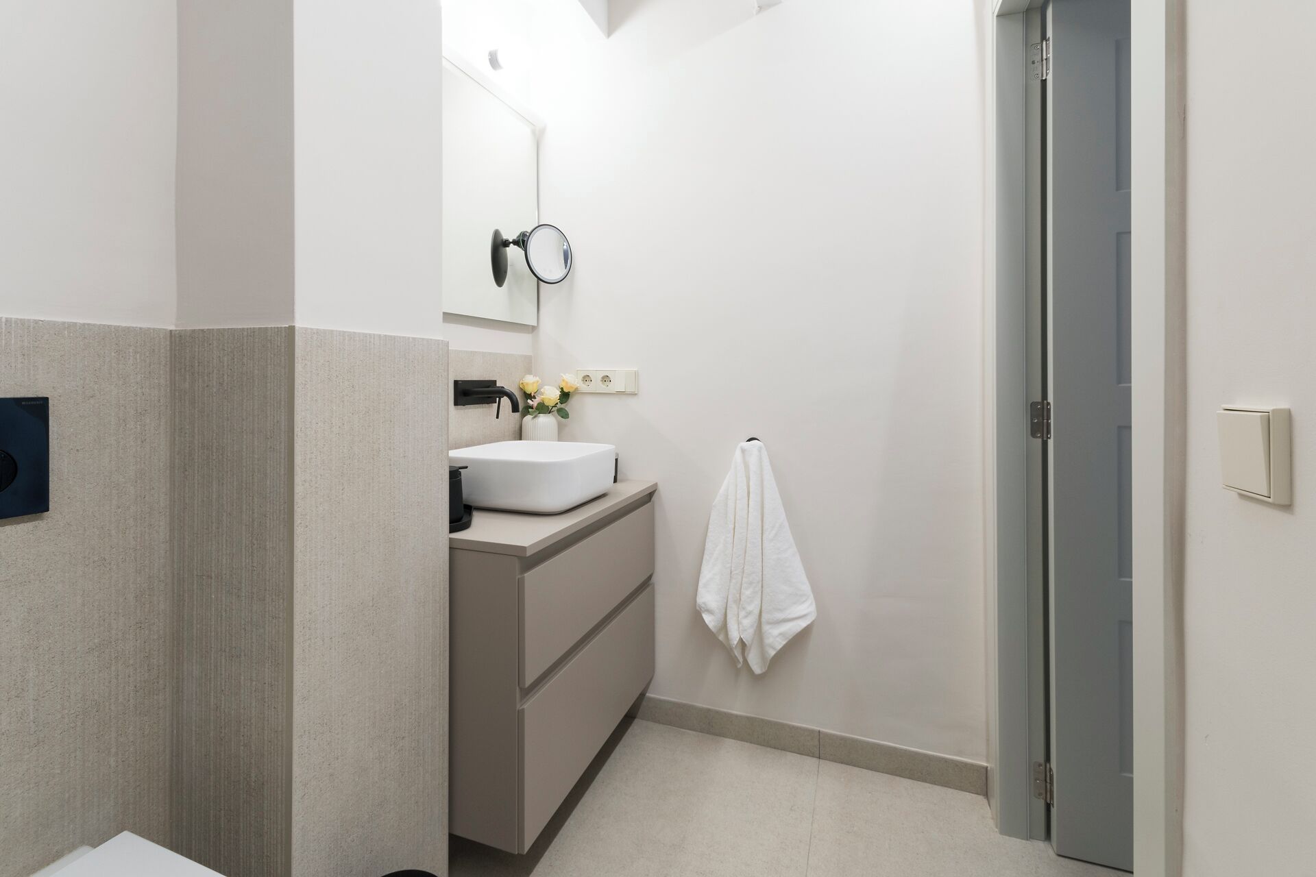 Une salle de bain moderne avec un lavabo blanc, un miroir et une serviette accrochée au mur.