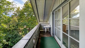 A covered balcony with a wooden railing, a green mat, and a table with chairs. - Apartment 'Brünnstein Room 60' with Mountain View, Shared Garden & Wi-Fi (Oberaudorf)
