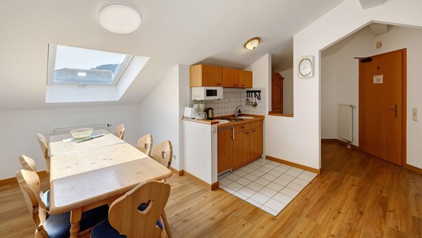 A compact kitchen with a skylight, a dining area with a table and chairs, and a view of the outside through the skylight. - Apartment 'Brünnstein Room 60' with Mountain View, Shared Garden & Wi-Fi (Oberaudorf)
