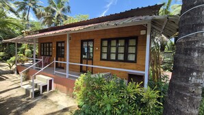 A wooden house with a porch, windows, and a staircase leading to the entrance. - Furtados Beach Cottages  (Benaulim)