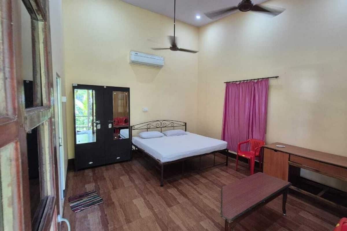A room with a bed, a desk, a chair, a ceiling fan, and a window with curtains.