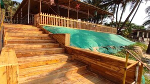 A wooden staircase leading to a covered area with a green tarp. - Furtados Beach Cottages  (Benaulim)