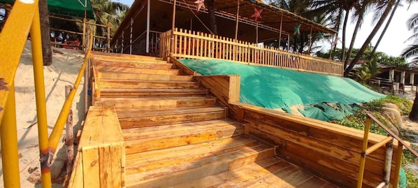 A wooden staircase leading to a covered area with a green tarp.
