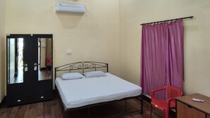A bedroom with a bed, a ceiling fan, a desk, a chair, and a mirror. - Furtados Beach Cottages  (Benaulim)
