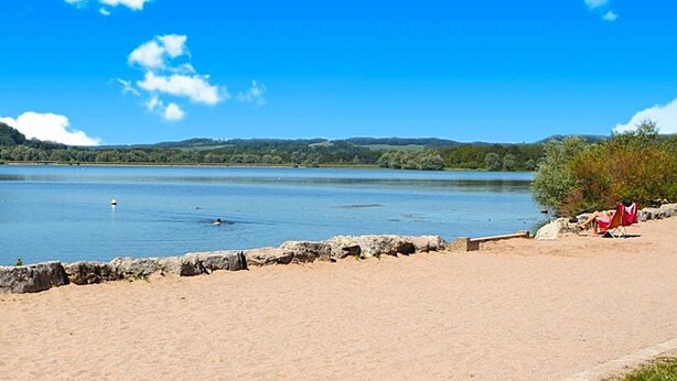 A sandy beach with a clear view of a lake and distant hills. - Unique and unusual: "Iliade" bus in a green and relaxing environment (Bourg)