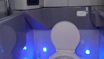 Une salle de bain moderne avec des toilettes blanches, un bidet et un sèche-mains.