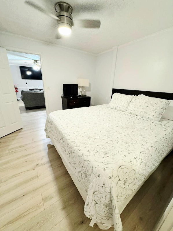 A bedroom with a bed, a nightstand, a TV, and a ceiling fan. - Creekside Retreat cozy studio with fitness center in charming Stockbridge (Stockbridge)