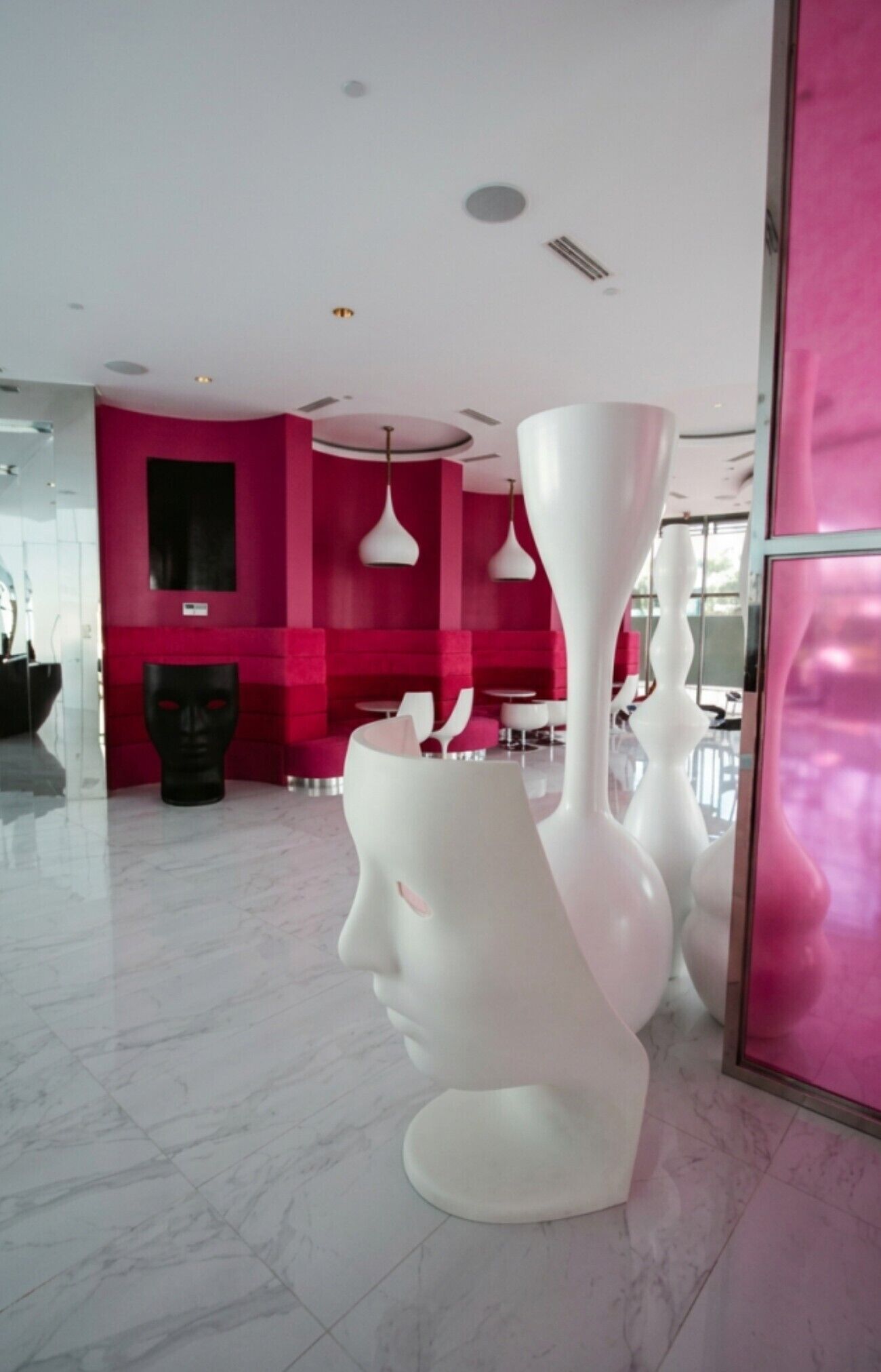 A modern interior with a marble floor, a pink wall, and white furniture.