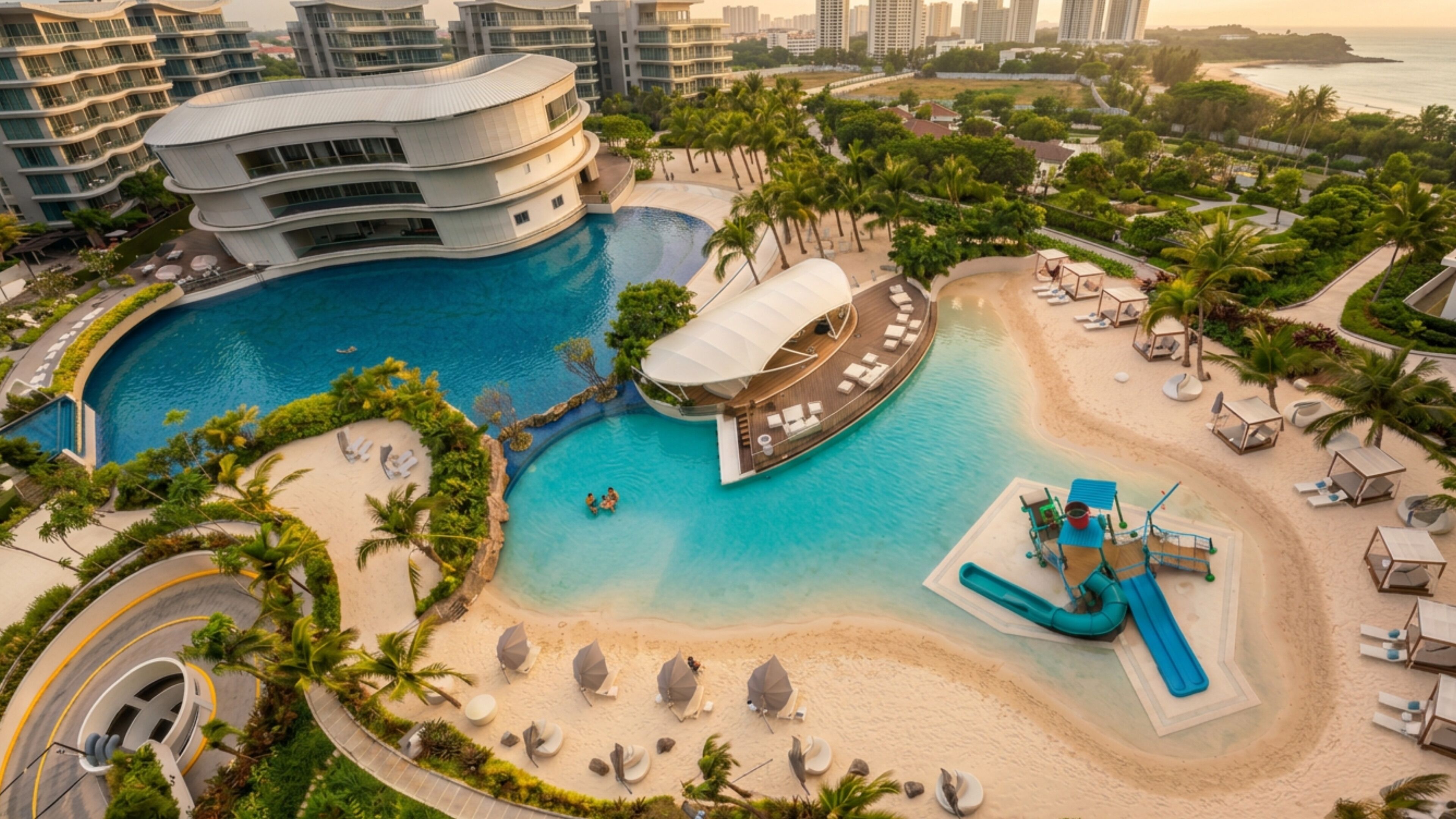 Ein Resort mit großem Schwimmbad, Strandbereich und einem modernen Gebäude mit Balkonen.