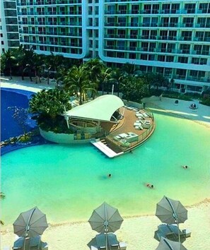 Un resort con piscina, zona de playa y un edificio de techo curvo.