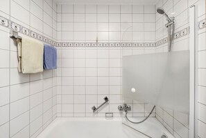 A shower with a handheld showerhead, a handheld showerhead, and a handheld showerhead.