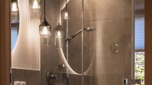 A modern bathroom with a glass-enclosed shower, a wooden vanity, and pendant lighting.