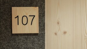 A wooden sign with the number 107 on a carpeted floor next to a wooden wall.