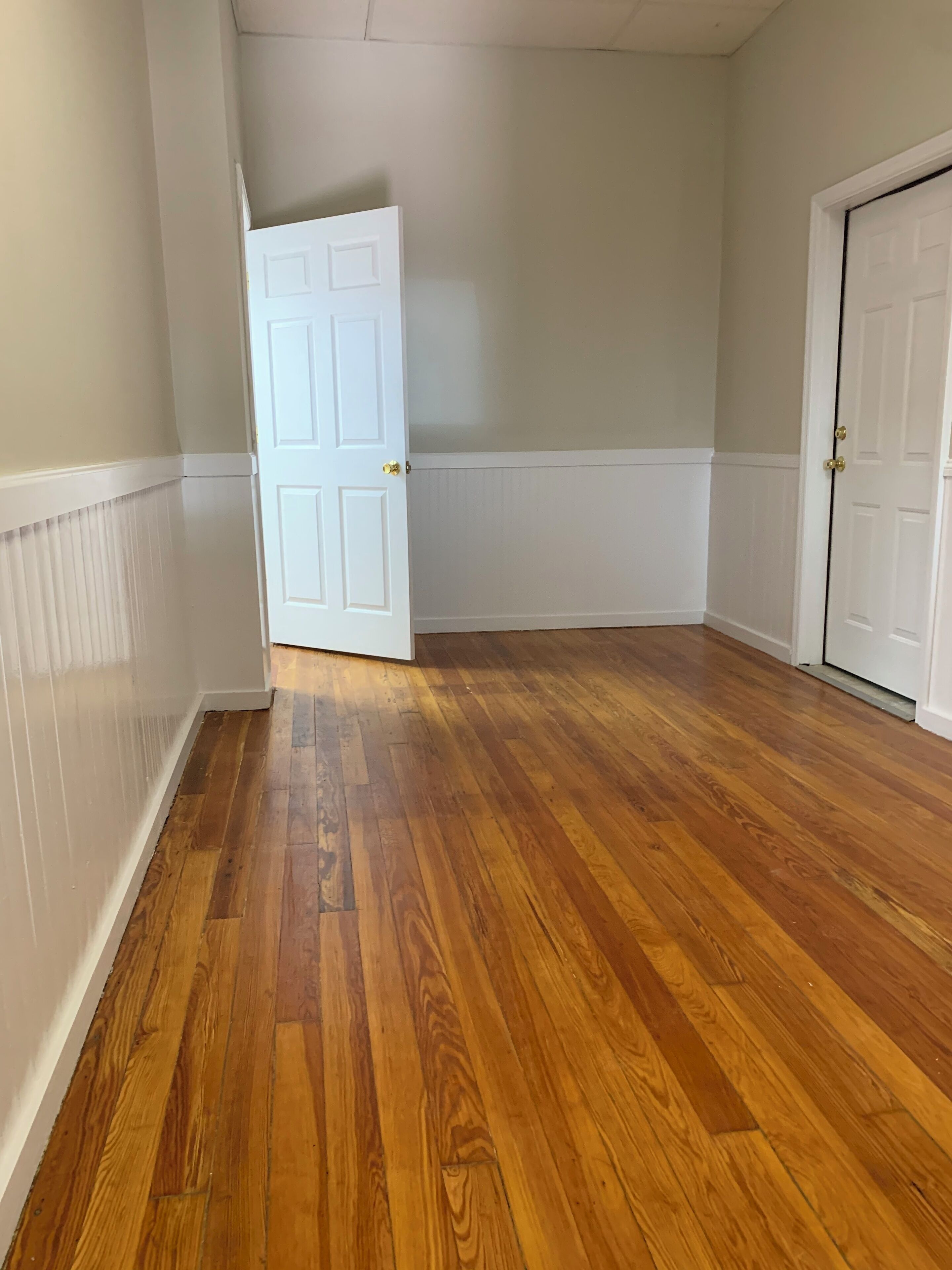 A hallway with wooden flooring and white walls.