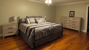 A bedroom with a bed, nightstands, a dresser, a ceiling fan, and wooden flooring. - Repurposed space upstairs on LaFayette Square (LaFayette)
