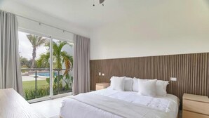 A modern bedroom with a large bed, a wooden nightstand, and a desk. - Garden View Relaxing Retreat (Punta Cana)