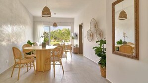 A dining area with a round table and wicker chairs, a large mirror, and a potted plant. - Garden View Relaxing Retreat (Punta Cana)