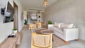 A modern living room with a sofa, dining table, chairs, and a TV. - Garden View Relaxing Retreat (Punta Cana)